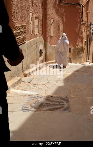 Femme mozabite voilée en haik blanc dans la rue de Beni Isguen. Beni Isguen est l'un des 5 Ksars (colonie fortifiée) de la vallée du Mzab. Province de Ghardaia. Sahara du Nord. Algérie Banque D'Images