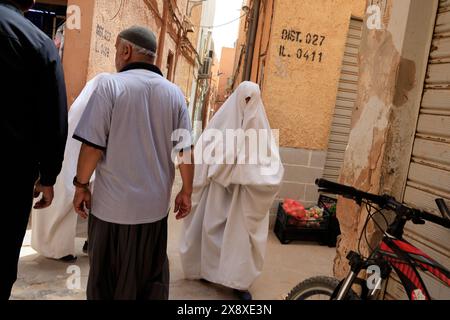 Femme mozabite voilée en haik blanc dans la rue de Beni Isguen. Beni Isguen est l'un des 5 Ksars (colonie fortifiée) de la vallée du Mzab. Province de Ghardaia. Sahara du Nord. Algérie Banque D'Images