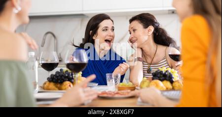 Des femmes heureuses se sont rassemblées autour d'une table festive ; participant à des discussions animées et appréciant les délices du vin Banque D'Images