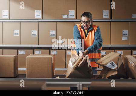 Ouvrière rebelle agressive brisant des boîtes au travail, elle est frustrée et en colère Banque D'Images