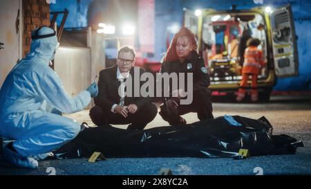 Scène de nuit du film détective : enquêteurs demandant à être montré une obus de balle de la preuve marquée. Les médecins légistes et la police collaborent pour déterminer la cause du décès de la victime. Banque D'Images