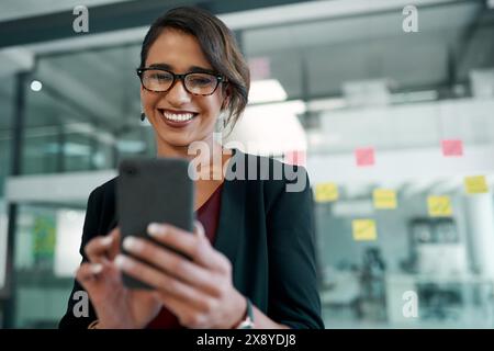 Téléphone, sourire et femme d'affaires dans le bureau en tapant un e-mail ou réseautage sur Internet. Communication, technologie et concepteur professionnel faire Banque D'Images