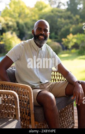 Un homme aîné afro-américain, portant une chemise légère, assis dehors Banque D'Images