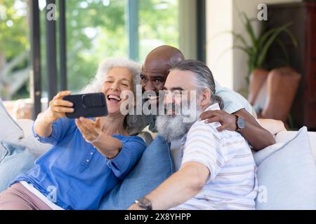 À la maison, divers amis seniors prenant selfie, riant ensemble Banque D'Images