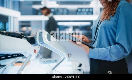 Gros plan d'une femme tenant et utilisant un ordinateur tablette dans un bureau industriel moderne de haute technologie. Mains d'une femme naviguant sur Internet, balayant dans la base de données de messagerie d'entreprise. Banque D'Images