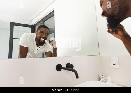 A la maison dans la salle de bain, homme afro-américain se brossant les dents Banque D'Images