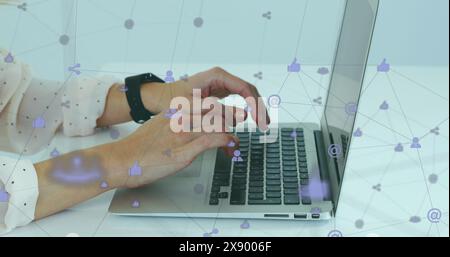 Image d'un réseau d'icônes numériques tournant sur la section médiane d'une femme à l'aide d'un ordinateur portable au bureau Banque D'Images