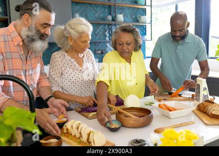 Divers amis seniors préparant la nourriture à la maison Banque D'Images