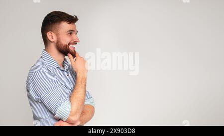 Jeune homme souriant et penser à la voiture sur l'espace libre Banque D'Images