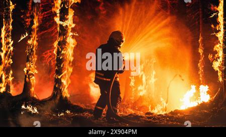 Pompier professionnel éteignant une grande partie hautement prioritaire de l'incendie de forêt. Pompiers hautement qualifiés travaillant dans des zones reculées difficiles avec des flammes atteignant la cime des arbres. Banque D'Images