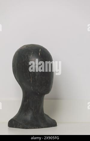 Tête de mannequin en bois noir vintage avec des fissures visibles sur un fond blanc – Design minimaliste et affichage antique Banque D'Images