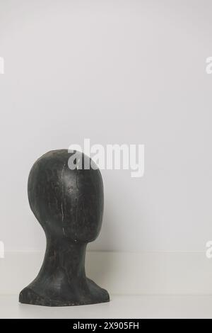 Tête de mannequin en bois noir vieilli avec des fissures distinctives sur fond blanc propre - pièce de décor antique minimaliste Banque D'Images