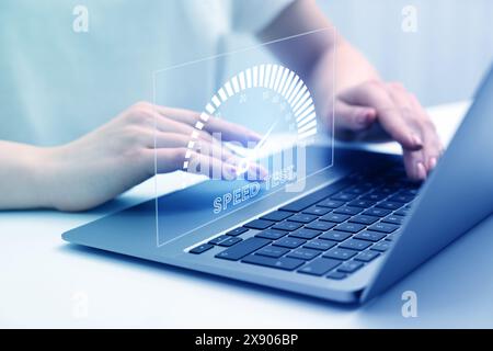 Test de vitesse. Femme utilisant un ordinateur portable à table, gros plan. Écran virtuel sur l'appareil Banque D'Images