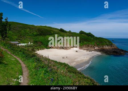 Vue sur la plage de sable blanc de Belvoir Bay du chemin côtier de Herm Island avec café de plage populaire occupé avec des visiteurs sur le beau ciel bleu du jour de mai et Banque D'Images