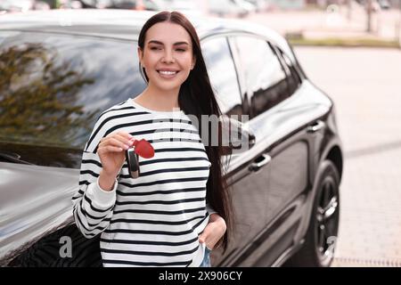 Femme tenant la clé à bascule de voiture près de son véhicule à l'extérieur Banque D'Images