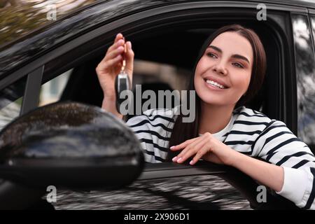 Femme tenant la clé à bascule de voiture à l'intérieur de son véhicule Banque D'Images