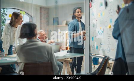 Équipe d'affaires multiethnique discutant de stratégie dans une salle de réunion au bureau. Brainstorming de concepteur masculin latin avec les chefs de service et décider d'une campagne marketing pour le lancement de nouveaux produits Banque D'Images