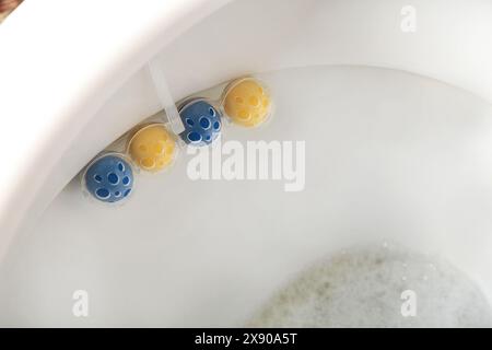 Nettoyez la cuvette des toilettes avec des boules nettoyantes et rafraîchissantes. Boules multicolores de nettoyant pour cuvette de toilettes. Vue de dessus Banque D'Images
