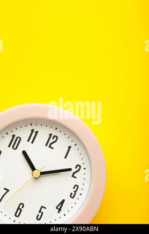 Horloge rose sur fond jaune. Vue de dessus. Photo verticale Banque D'Images