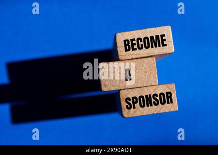 Devenez un sponsor mots écrits sur des blocs de bois avec fond bleu. Conceptuel Devenez un symbole de sponsor. Copier l'espace. Banque D'Images