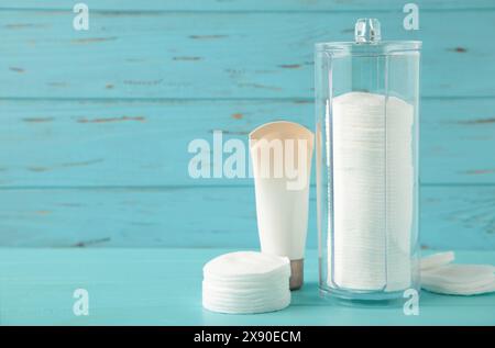 Paquet de crème avec des tampons de coton dans le récipient sur fond bleu. Produits de beauté pour le soin de la peau. Vue de dessus Banque D'Images