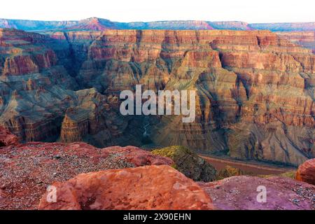 Vue rapprochée des formations géologiques vives du Grand Canyon avec une rivière sereine serpentant au fond du canyon. Banque D'Images