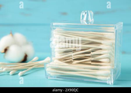 Bâtonnets de coton dans des récipients avec fleur de coton sur fond bleu. Vue de dessus Banque D'Images