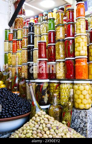 Image d'aliments conservés dans des bocaux empilés verticalement - olives, citrons, oignons, poivrons - dans un marché au Maroc. Olives fraîches au premier plan 4 Banque D'Images