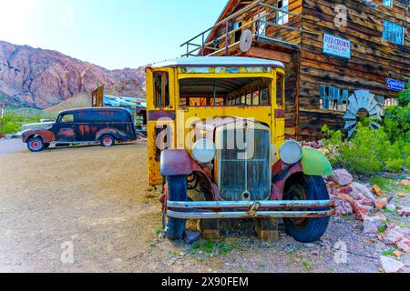 Nelson, Nevada - 15 avril 2024 : vieux et minable bus vintage et voiture classique garés par une grange en bois. Banque D'Images