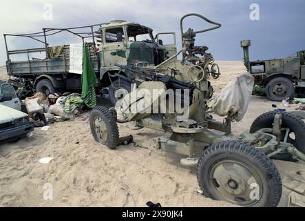 Première Guerre du Golfe : 4 mars 1991 Un canon antiaérien à quatre roues ZPU-4 14.5mm KPV remorqué soviétique abandonné parmi des véhicules militaires épaves et brûlés, faisant partie d'un convoi irakien qui a été attaqué avec des bombes à sous-munitions par l'USAF environ une semaine auparavant sur la route 801, la route vers Um Qasr, au nord de Koweït City. Banque D'Images