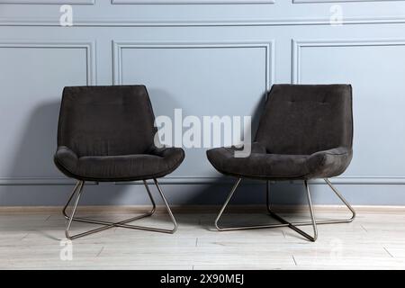 Fauteuils confortables près du mur gris dans la chambre Banque D'Images