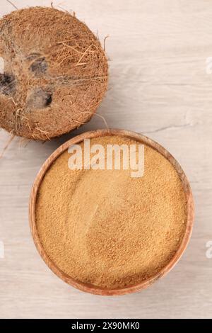 Sucre de noix de coco dans un bol et fruits sur une table en bois clair, vue de dessus Banque D'Images