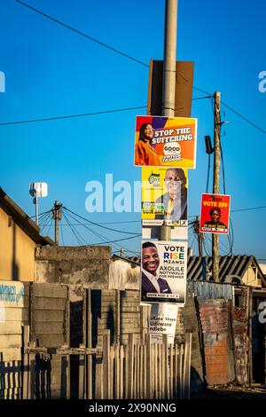 Khayelitsha. Affiches électorales pour divers partis se bousculant pour l'espace sur les pôles et les votes des peuples lors des élections de mai 29/2024 en Afrique du Sud. En arrière-plan les cabanes et les toilettes extérieures du canton. Banque D'Images