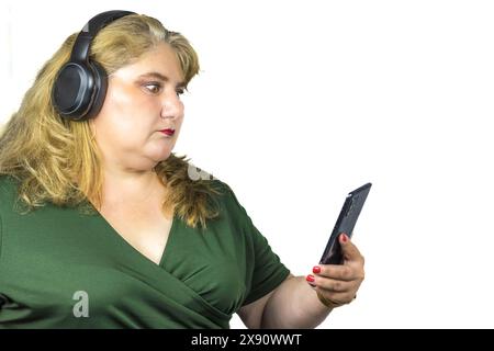 Cette photographie capture une femme blanche caucasienne d’âge moyen souffrant d’obésité légère, immergée dans le monde numérique à travers son smartphone Banque D'Images