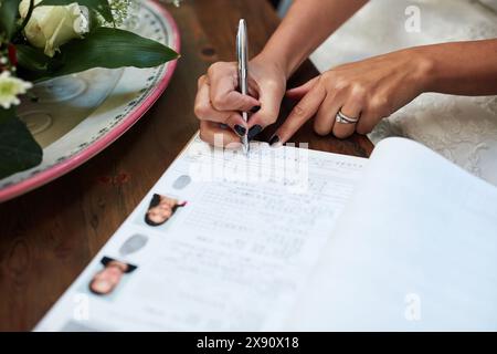 Mariage, documents et main de femme avec signature pour contrat légal, engagement et licence. Certificat, paperasse et personne avec écrit dessus Banque D'Images