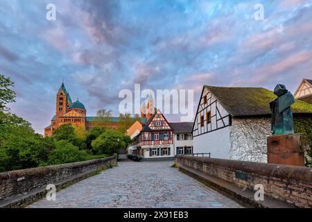 Fachwerkhaeuser und eine Statue auf einer Bruecke mit Blick auf eine Kirche im Abendhimmel, die eine friedliche historische Atmosphaere bietet Banque D'Images