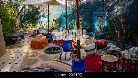 Une terrasse avec plusieurs tables, coussins et parasols aménagés pour les repas en plein air. La scène montre une salle à manger extérieure fonctionnelle et accueillante, comple Banque D'Images