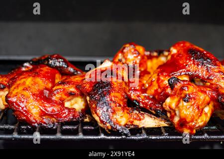 Ailes de poulet grillées sur un gril à gaz noirci marques de charbon. Banque D'Images