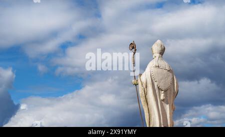 Religion chrétienne et spiritualité. Statue antique d'évêque ou de pape avec crosier et mitre contre le ciel céleste Banque D'Images