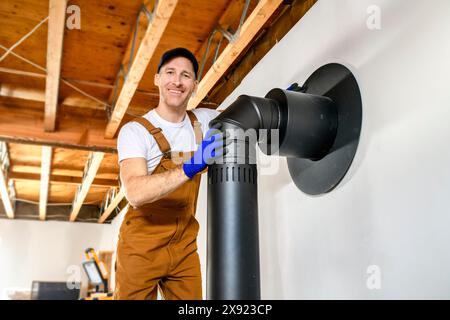 travailleur masculin préparant une installation de cheminée pour un poêle de chauffage moderne et économe en énergie. Banque D'Images