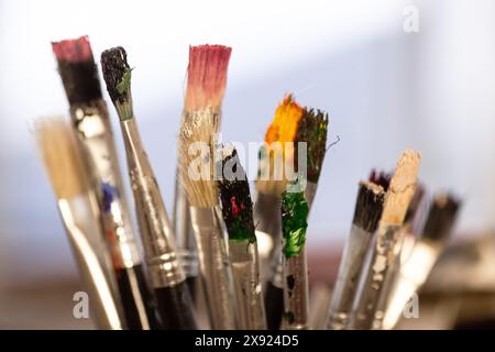 Une image vive en gros plan de divers pinceaux avec des poils colorés, utilisés par un artiste dans un studio de création. Banque D'Images