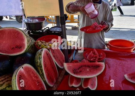 Srinagar, Inde. 28 mai 2024. Un vendeur prépare des assiettes pleines de pastèque pour les clients lors d'une journée d'été brûlante. La vallée du Cachemire a connu une hausse significative des températures, plusieurs zones enregistrant les températures les plus élevées depuis des décennies. Le Département météorologique a également prédit la poursuite de la canicule le mois prochain. (Crédit image : © Saqib Majeed/SOPA images via ZUMA Press Wire) USAGE ÉDITORIAL SEULEMENT! Non destiné à UN USAGE commercial ! Banque D'Images