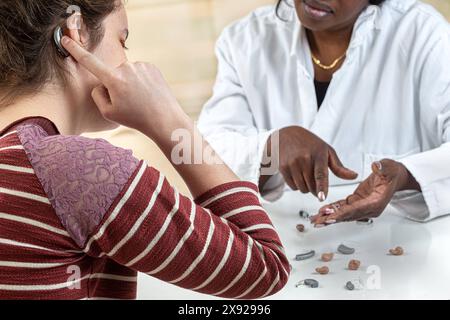 Patient essayant différents types de prothèses auditives. Bavardage avec ses problèmes auditifs audioprothésistes chez une jeune femme 016454 023 Banque D'Images