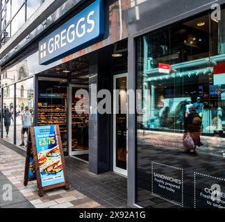 Les piétons passent devant une vitrine de boulangerie Greggs à Belfast, en irlande du Nord. Banque D'Images