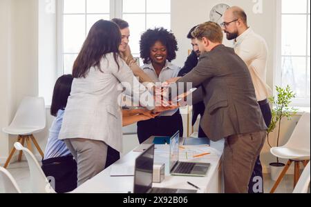 Gens d'affaires debout dans Un cercle et empilant les mains ensemble dans le bureau Banque D'Images