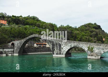 Le magnifique Pont de la Madeleine - Pont du Diable - sur la rivière Serchio en Toscane, Italie près de Lucques, avec des arbres verts sur les pentes des collines. Banque D'Images