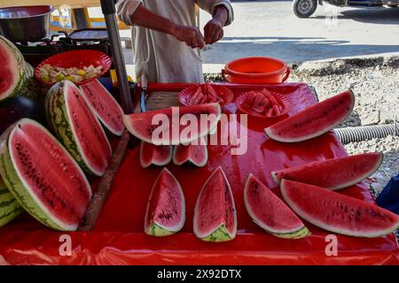 Srinagar, Inde. 28 mai 2024. Un vendeur prépare des assiettes pleines de pastèque pour les clients lors d'une journée d'été brûlante. La vallée du Cachemire a connu une hausse significative des températures, plusieurs zones enregistrant les températures les plus élevées depuis des décennies. Le Département météorologique a également prédit la poursuite de la canicule le mois prochain. (Photo de Saqib Majeed/SOPA images/Sipa USA) crédit : Sipa USA/Alamy Live News Banque D'Images