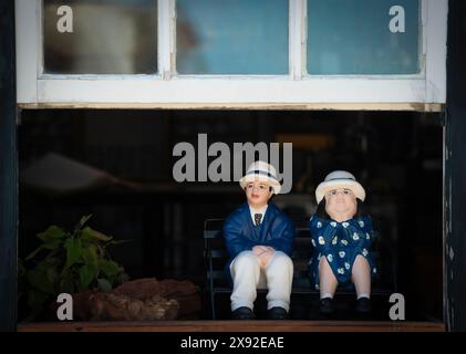 Rua Josefa de Óbidos, Óbidos, Portugal. De petites figurines masculines et féminines en céramique peintes se trouvent dans une fenêtre de café près de la place Padrao Camoniano, à l'entrée du village médiéval fortifié en pierre. Banque D'Images