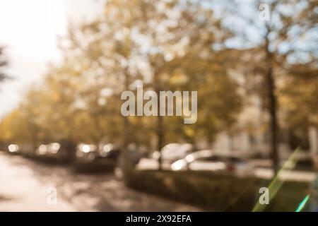 Une photo floue d'une rue avec des voitures et des arbres. La photo a une qualité rêveuse et brumeuse, comme si elle était prise à travers une fenêtre brumeuse. Banque D'Images