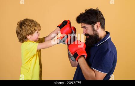 Boxeur enfant avec entraîneur à la formation de boxe. Petit fils faisant de l'exercice de boxe avec le père dans le gymnase. Enfant et entraîneur en ring de boxe. Garçon et entraîneur en boxe Banque D'Images